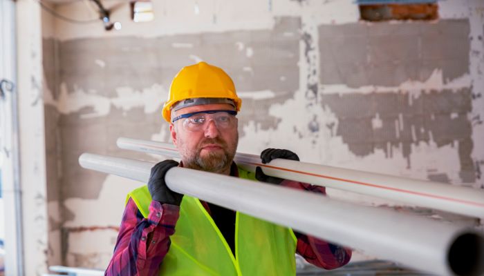 man carrying 2 pipes